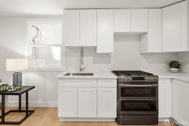 830 47th St, Emeryville, CA 94608 - kitchen with range with two ovens, a sink, white cabinetry, light wood finished floors, and light stone counters