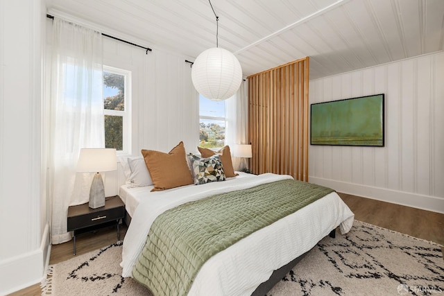 bedroom featuring baseboards, multiple windows, and wood finished floors