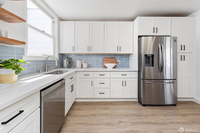 kitchen featuring a sink, light wood finished floors, appliances with stainless steel finishes, and white cabinets