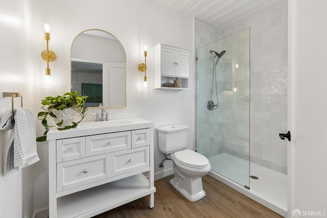 full bath featuring vanity, wood finished floors, toilet, baseboards, and a tile shower