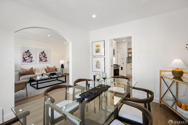 dining area featuring arched walkways, baseboards, recessed lighting, and wood finished floors