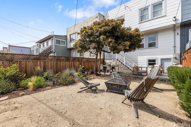 exterior space with fence, a fire pit, and stairs