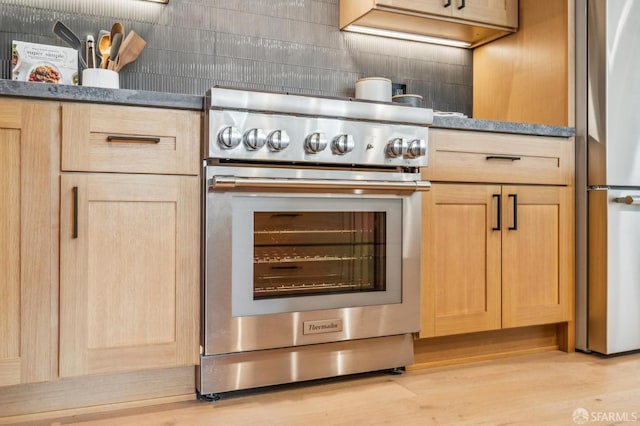 kitchen with decorative backsplash, light brown cabinets, light wood-style floors, and stainless steel appliances