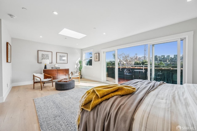 bedroom featuring access to exterior, light wood finished floors, baseboards, recessed lighting, and a skylight