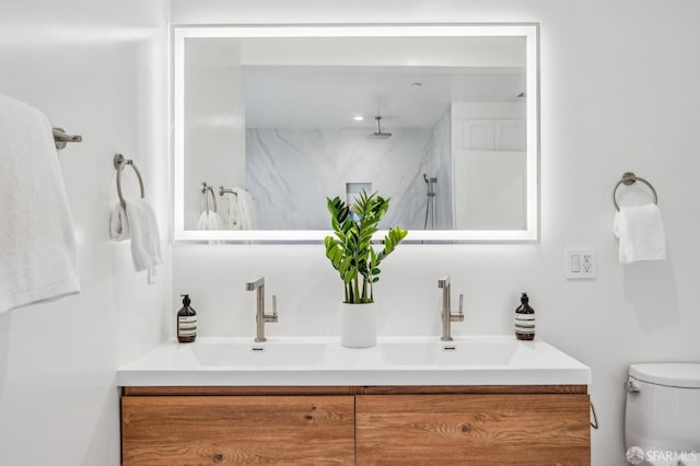 bathroom featuring double vanity, toilet, walk in shower, and a sink