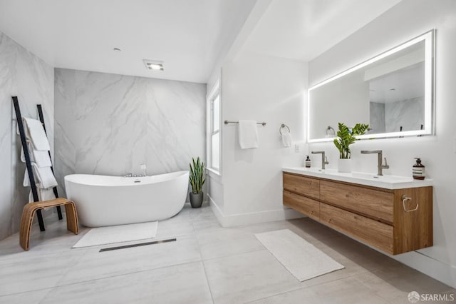 full bath featuring a sink, a freestanding tub, baseboards, and double vanity