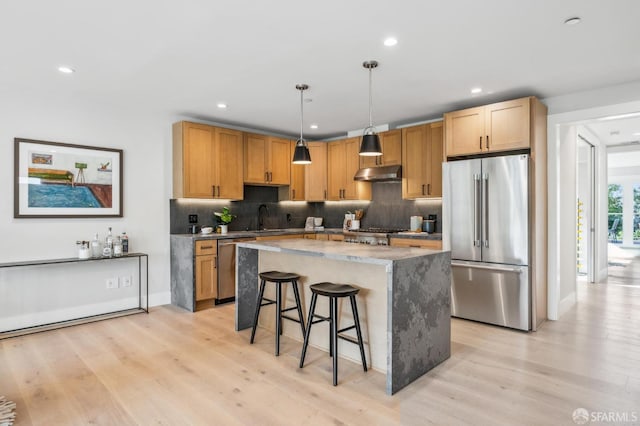 kitchen with under cabinet range hood, light wood-style floors, appliances with stainless steel finishes, and a sink