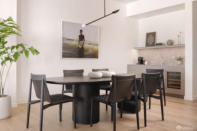 dining area with baseboards, wood finished floors, wet bar, and beverage cooler