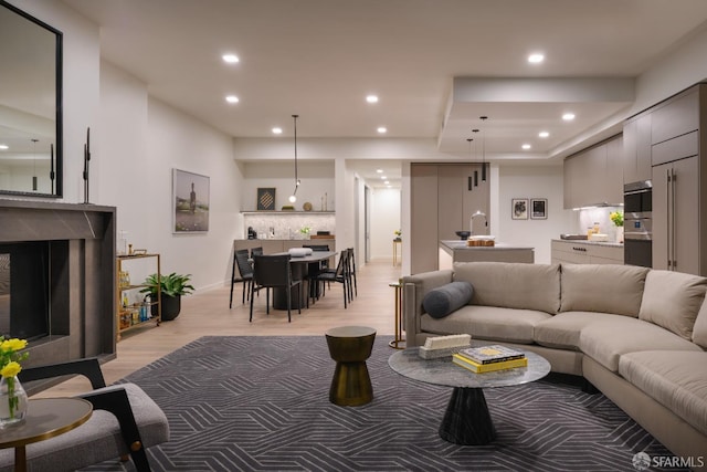 living room featuring a high end fireplace, light wood-style flooring, and recessed lighting