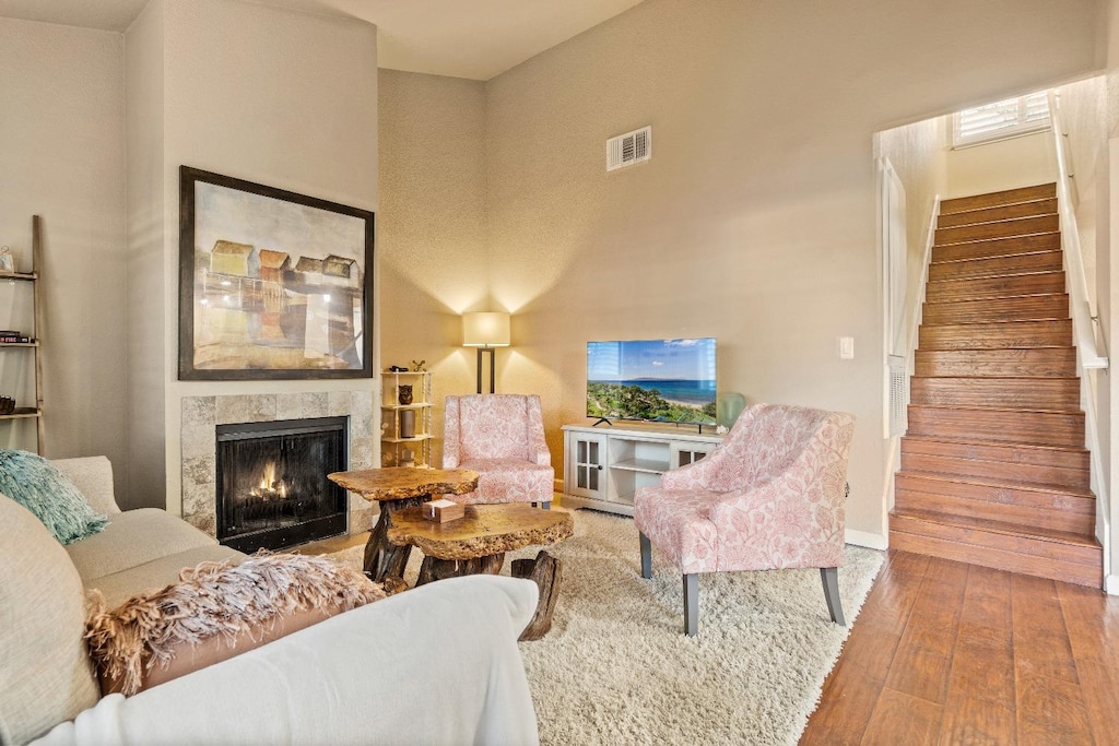 living room featuring a towering ceiling, wood-type flooring, and a high end fireplace