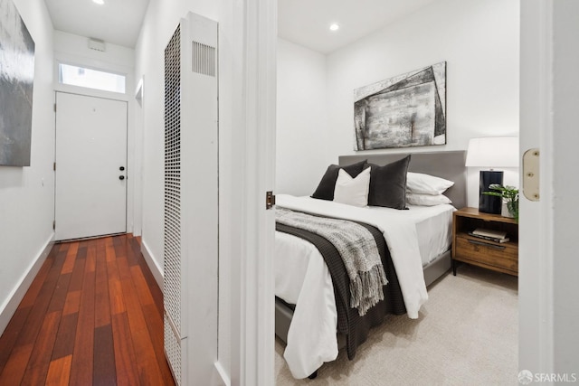 bedroom with recessed lighting, wood finished floors, baseboards, a closet, and a heating unit