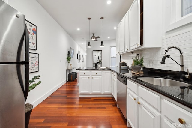 kitchen featuring a peninsula, appliances with stainless steel finishes, dark countertops, and a sink