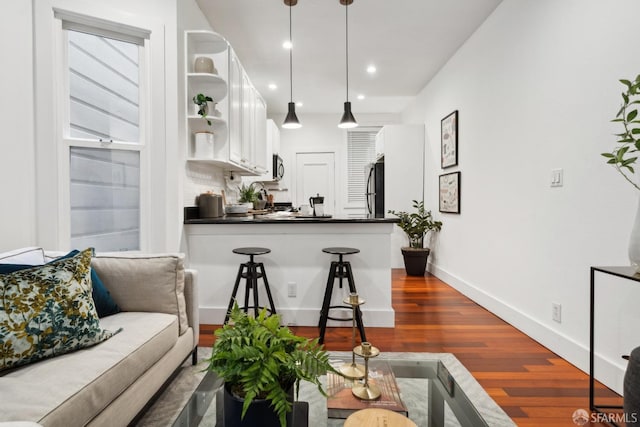 kitchen with dark wood finished floors, dark countertops, refrigerator, white cabinetry, and open shelves