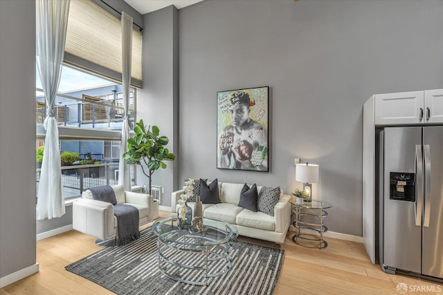 living room with a towering ceiling and light hardwood / wood-style floors