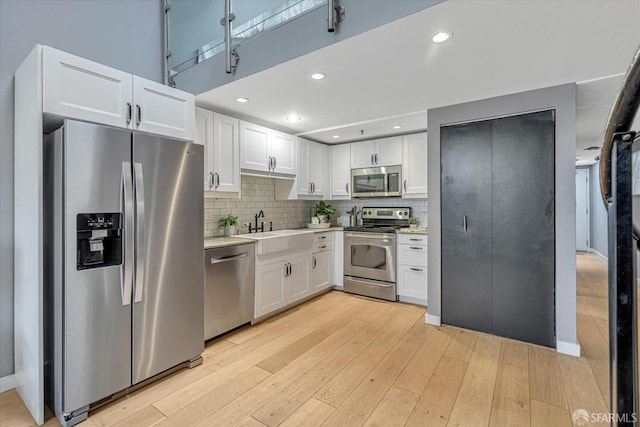 kitchen with white cabinetry, sink, light hardwood / wood-style flooring, and appliances with stainless steel finishes