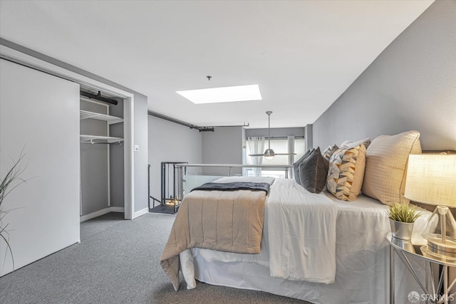 bedroom with a skylight, dark carpet, and a closet