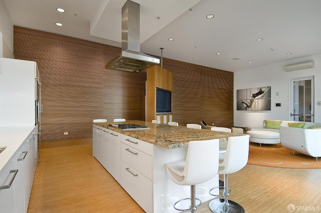 1160 Mission St Unit 2212, San Francisco, CA 94103 - kitchen with wall chimney exhaust hood, modern cabinets, a kitchen island, light wood-type flooring, and stainless steel gas stovetop