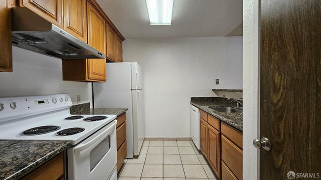 2011 Market Ave Unit 324, San Pablo, CA 94806 - kitchen with white appliances, under cabinet range hood, brown cabinets, dark stone countertops, and light tile patterned flooring