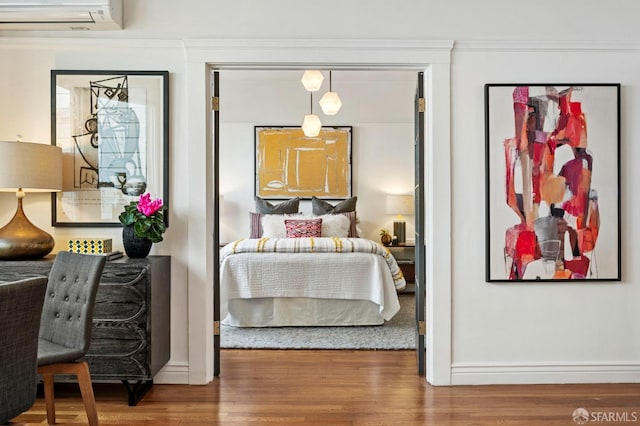 bedroom featuring a wall unit AC and wood finished floors