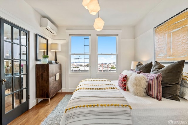 bedroom with an AC wall unit, wood finished floors, and baseboards