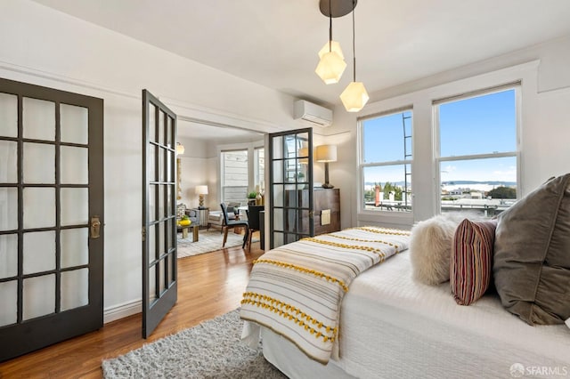 bedroom featuring french doors, a wall mounted AC, and wood finished floors