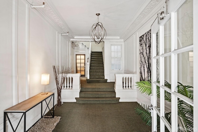 interior space with a chandelier, ornamental molding, stairs, dark carpet, and a decorative wall