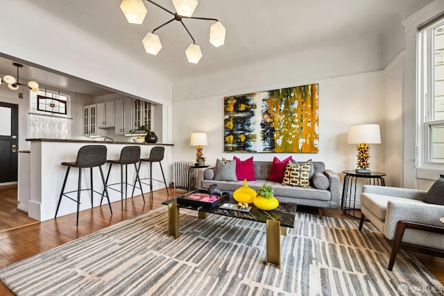 living area featuring a chandelier, radiator heating unit, and wood finished floors