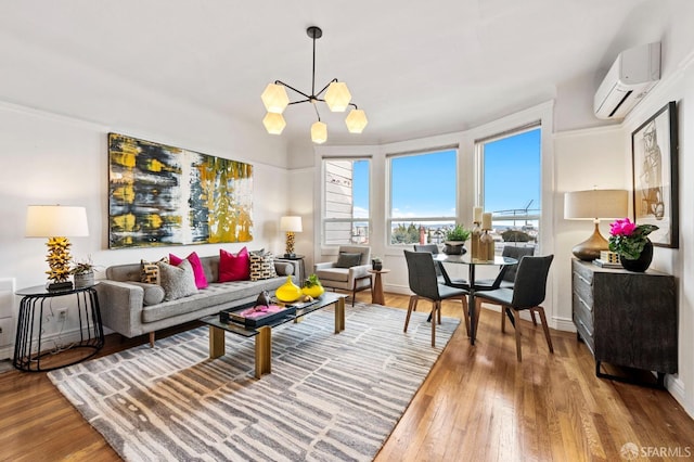 living room with a chandelier, a wall mounted air conditioner, baseboards, and wood finished floors