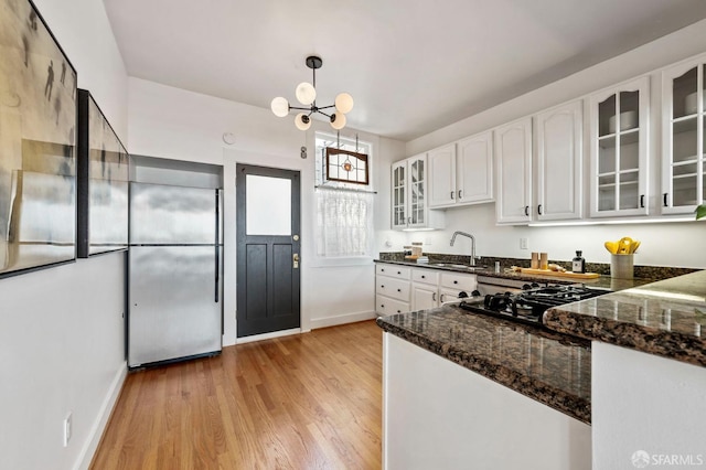 kitchen with white cabinets, light wood-type flooring, stainless steel built in refrigerator, and a sink