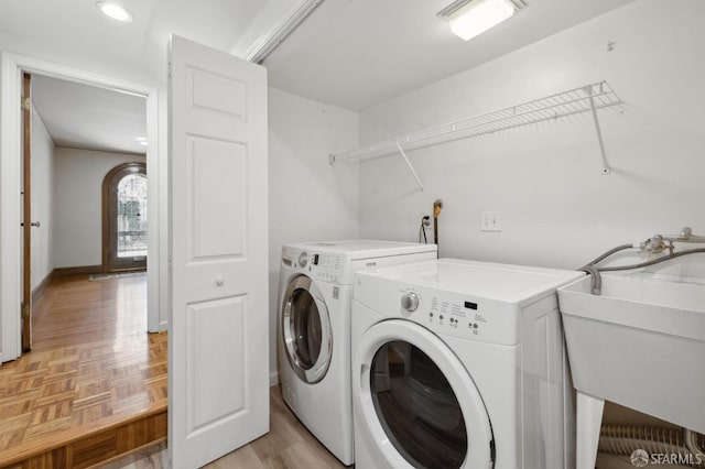 washroom featuring washer and clothes dryer, a sink, baseboards, laundry area, and parquet flooring