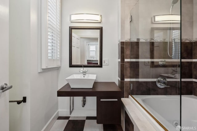 bathroom featuring tile patterned floors, baseboards, tiled shower / bath combo, and a sink