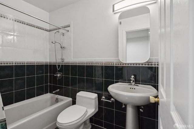 bathroom with a wainscoted wall, toilet, tile walls, and shower / bathtub combination