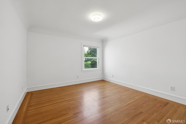 spare room featuring baseboards and wood finished floors