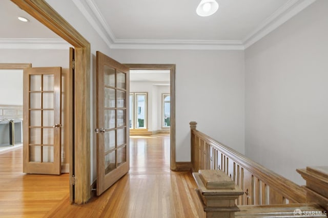 hallway featuring french doors, baseboards, crown molding, and light wood-style floors