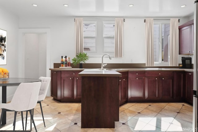 kitchen with dark brown cabinets, recessed lighting, light tile patterned flooring, and a sink