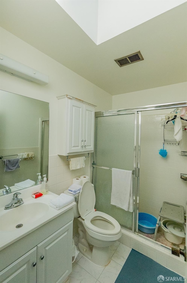 bathroom featuring visible vents, tile walls, toilet, a stall shower, and vanity