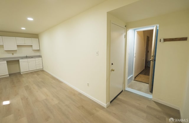 kitchen featuring white cabinetry, light wood-style floors, and a sink