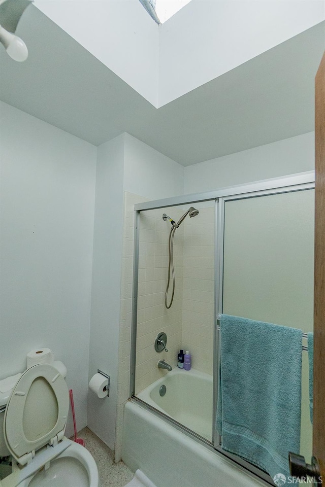 bathroom featuring combined bath / shower with glass door, toilet, and speckled floor