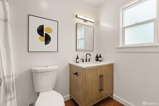 bathroom featuring toilet, baseboards, wood finished floors, and vanity