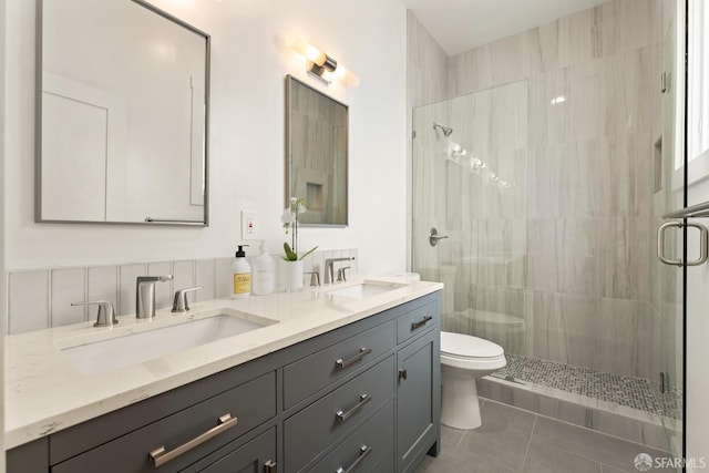 bathroom featuring tile patterned flooring, a sink, a shower stall, and toilet