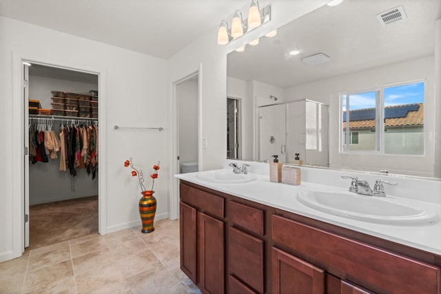 bathroom featuring double vanity, a stall shower, visible vents, and a sink