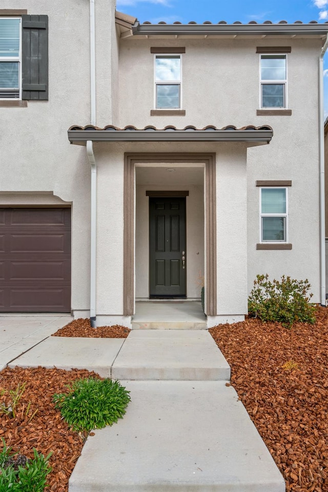 property entrance with an attached garage and stucco siding