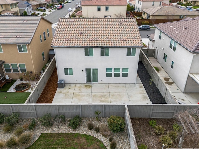 exterior space with central air condition unit, a patio area, a fenced backyard, and a tile roof