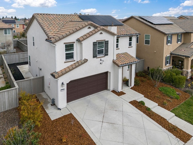 mediterranean / spanish house featuring stucco siding, fence, concrete driveway, and a tiled roof