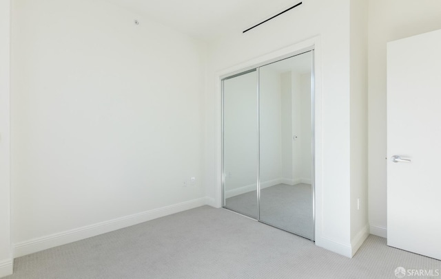 unfurnished bedroom featuring light colored carpet and a closet