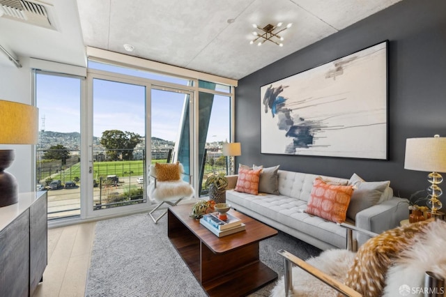 living area featuring visible vents, a wall of windows, and wood finished floors