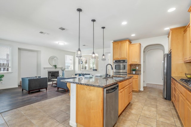 549 Fresian Dr, Oakdale, CA 95361 - kitchen featuring stainless steel appliances, a sink, dark stone countertops, an island with sink, and open floor plan