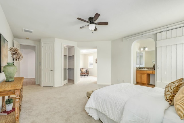 549 Fresian Dr, Oakdale, CA 95361 - bedroom featuring arched walkways, light colored carpet, connected bathroom, and baseboards