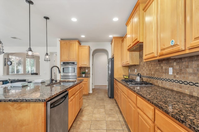 549 Fresian Dr, Oakdale, CA 95361 - kitchen with stainless steel appliances, arched walkways, a sink, light brown cabinets, and decorative backsplash