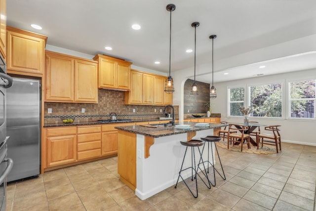 549 Fresian Dr, Oakdale, CA 95361 - kitchen featuring appliances with stainless steel finishes, a sink, decorative backsplash, light tile patterned floors, and a kitchen island with sink